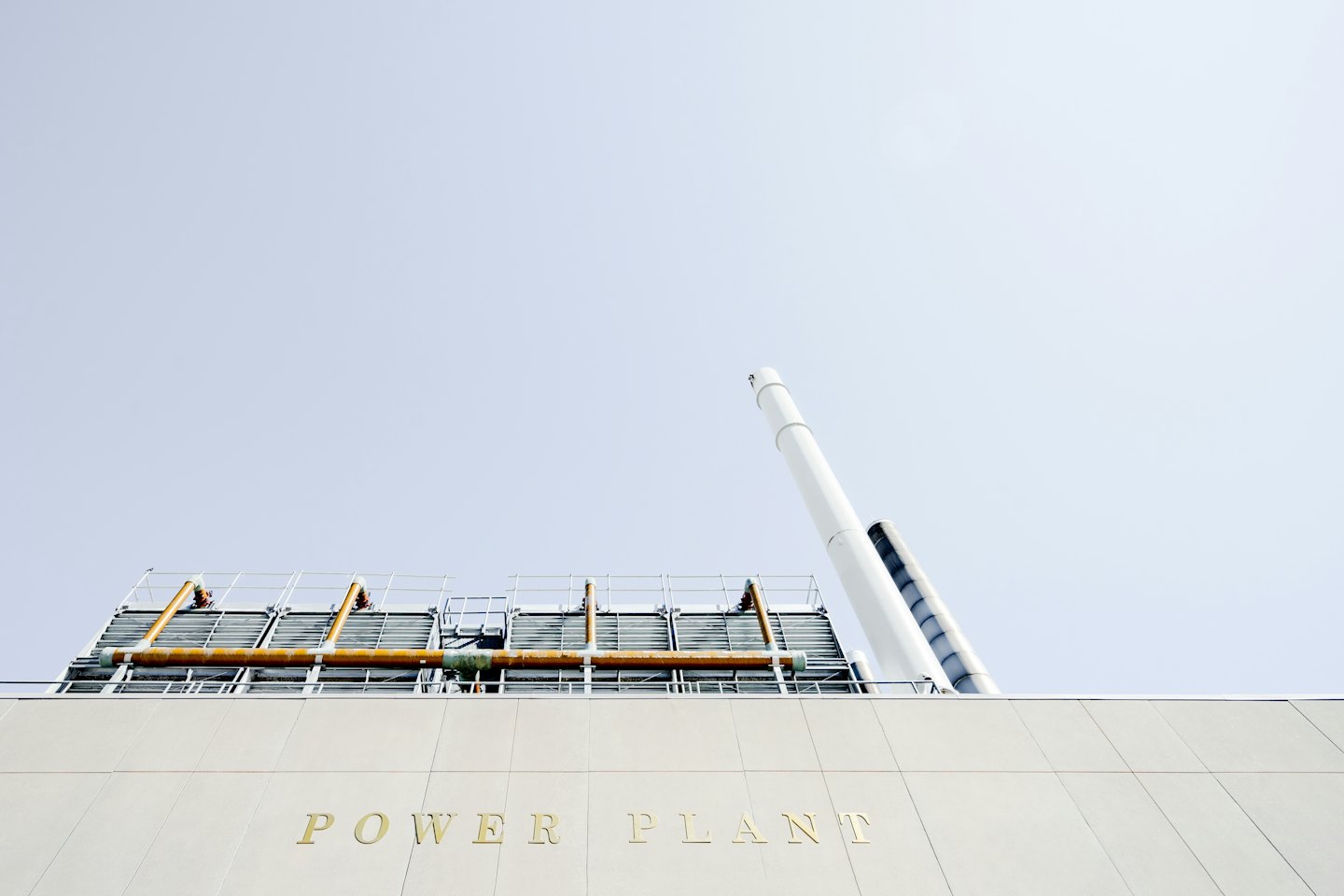 Facciata di una moderna centrale elettrica con scritte dorate e ciminiere bianche.