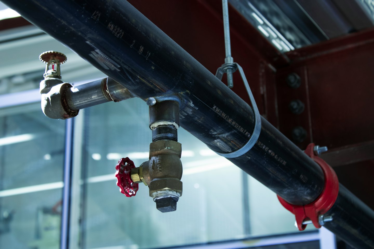 Tubi industriali e testina di sprinkler su una trave del soffitto.