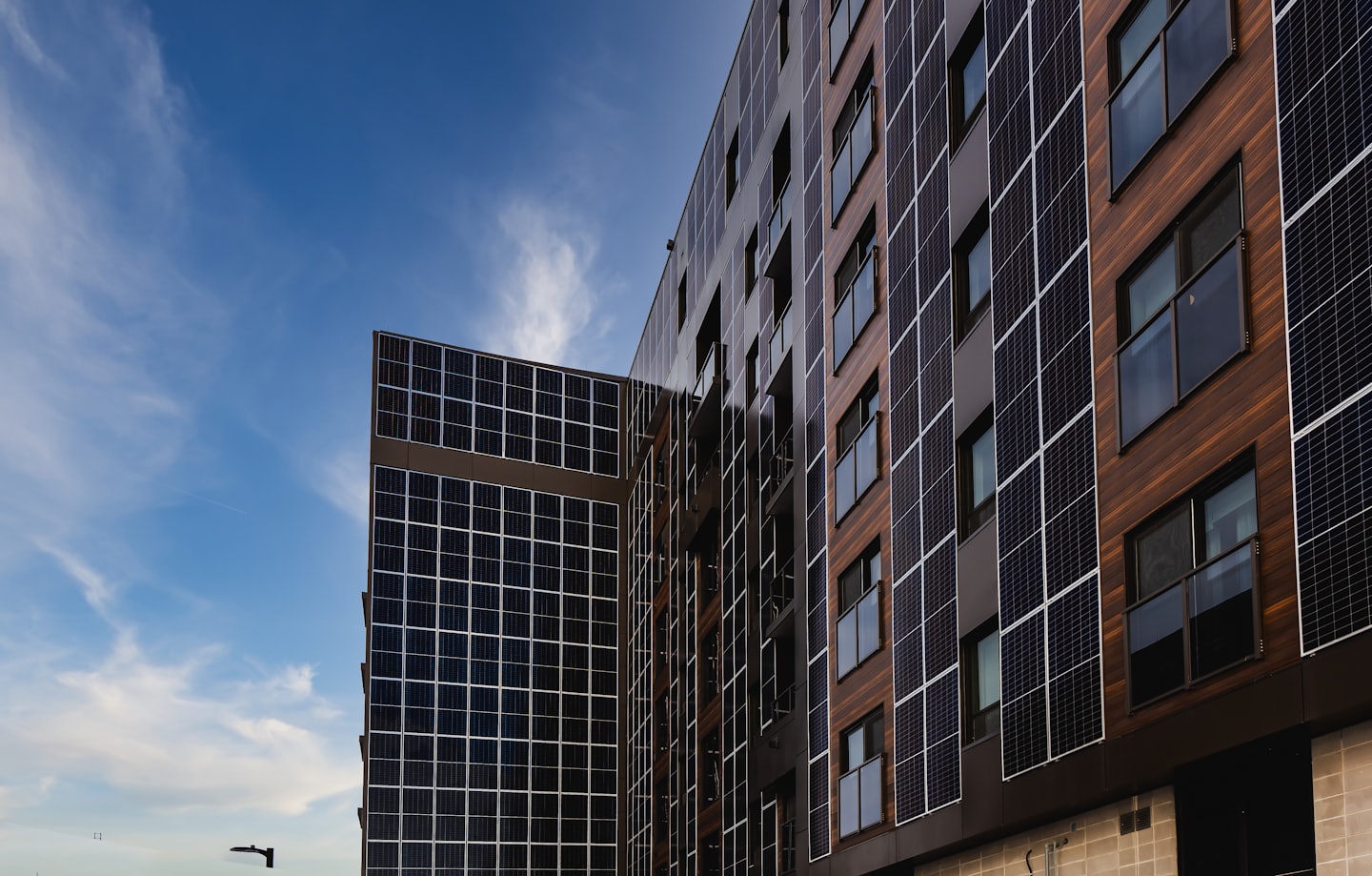 Facciata di un edificio moderno con pannelli solari e rivestimenti in legno.